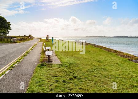 Bänke auf Gras entlang einer Küstenstraße bei Sonnenuntergang im Sommer Stockfoto