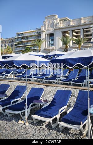 Viele blaue Liegestühle und Sonnenschirme am Strand mit Kieselsteinen in Cannes, Frankreich Stockfoto