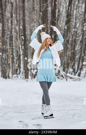 Junge Frau posiert auf Schlittschuhen auf der Eislaufbahn im Winterpark. Stockfoto