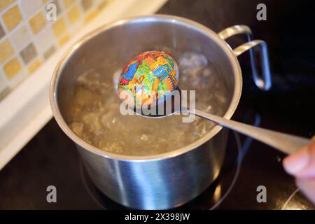 MOSKAU - 30. April 2016: Hand kommt aus kochendem Wasser Ei mit Deckel mit Druck in der Küche. Es gibt Tradition, in orthodoxen EAS Bilder auf Eier zu setzen Stockfoto