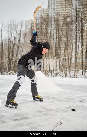 Ein Hockeyspieler, der auf der Eislaufbahn im Freien Puck spielt. Stockfoto