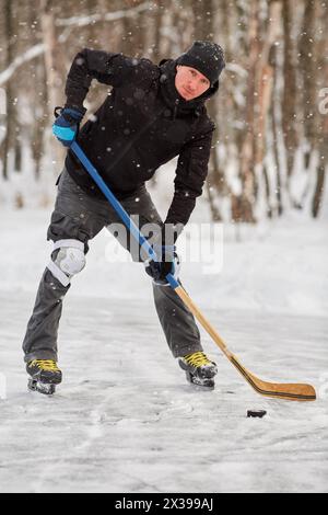 Ein Hockeyspieler, der auf der Eislaufbahn im Freien Puck spielt. Stockfoto