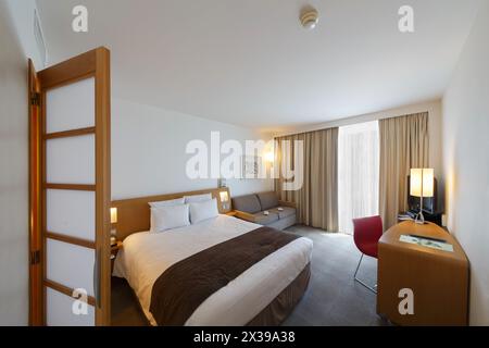 MONTE CARLO, MONACO - 3. August 2016: Novotel Hotel, schöne Einrichtung des Hotelzimmers, Schlafzimmer mit Aussicht, Sofa und Fernseher Stockfoto