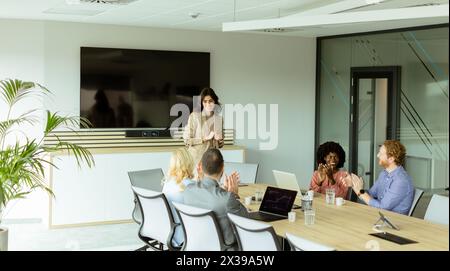 Die kompetente Frau präsentiert sich während eines Meetings vor Kollegen, wobei ihr Ausdruck Begeisterung und Führungsstärke zum Ausdruck bringt Stockfoto