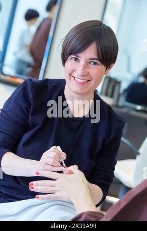 Kosmetikerin, die die Nägel des Kunden malt. Maniküre. Friseursalon und Schönheitsklinik. Stockfoto