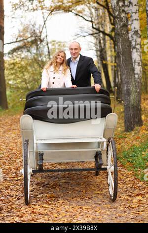 Glückliche Paare sind im weißen Bus im herbstgelben Park während eines romantischen Spaziergangs Stockfoto