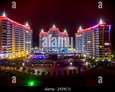 ALANYA, TÜRKEI - 16. August 2015: Drei Gebäude des Wohnkomplexes Azura Park Residence mit Farblicht bei Nacht, Luftbild Stockfoto