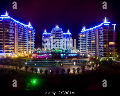ALANYA, TÜRKEI - 16. August 2015: Drei Gebäude des Wohnkomplexes Azura Park Residence mit abendlichem Farblicht bei Nacht, Luftbild Stockfoto