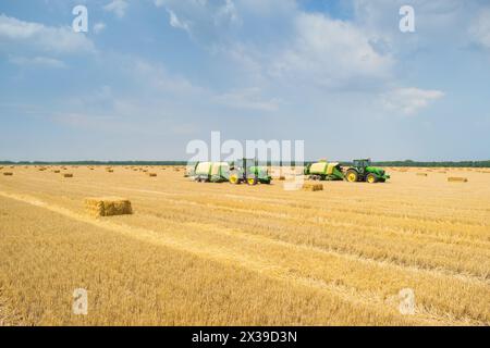 REGION KRASNODAR, RUSSLAND - 7. Juli 2015: Traktoren stellen Strohgepresste Steine auf gelbem Feld nach der Ernte her, im Jahr 2015 in der Region Krasnodar gesammelt haben Stockfoto