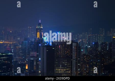 Nächtliche Wolkenkratzer mit heller Beleuchtung und Bergen in Hong Kong, China, Blick vom Queen Garden Stockfoto