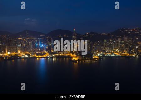 Wolkenkratzer mit heller Beleuchtung, Ufer und Berge in Hongkong, China bei dunkler Nacht, Blick vom New World Center Stockfoto