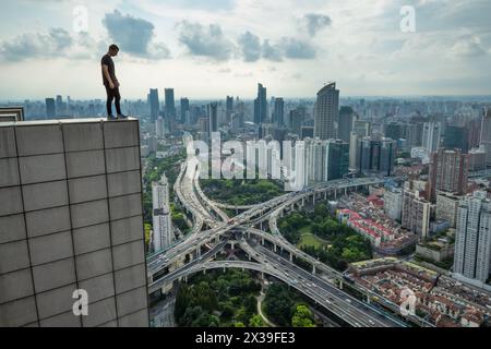 Der Mann steht auf dem Dach eines hohen Gebäudes und betrachtet den Verkehrsknotenpunkt in Shanghai, Blick vom K11-Gebäude Stockfoto