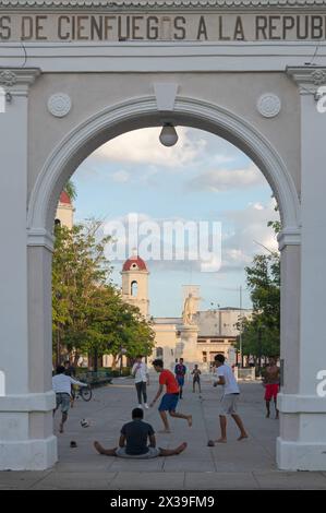 Jugendliche spielen am späten Nachmittag im Parque de Jose Marti vor dem Arc de Triomph Fußball. Parque Jose Marti, Central Cienfuegos, Kuba Stockfoto