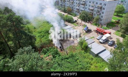 MOSKAU - 25. JUL 2015: Feuerwehrleute benutzen Schlauch auf Unfallstelle mit Rauch am sonnigen Sommertag in der Neustadt. Luftaufnahme Stockfoto