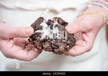 Ein frisch zubereiteter, warmer Oreo-Cookie im NY-Stil, der vom Bäcker auseinandergezogen wird. Der Keks ist mit einer weißen Schokoladencreme gefüllt Stockfoto