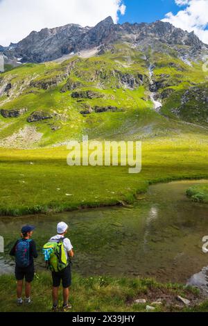 Ein paar Wanderer bewundern die wunderschöne Aussicht auf die Berge in den französischen Alpen. Peisey Valley, Savoie, Frankreich. Stockfoto