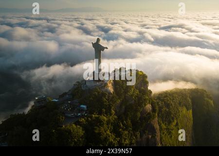 Rio de Janeiro, Brasilien - 11. April 2024: Dramatischer Blick auf die Christus-Erlöser-Statue auf dem Berg Corcovado über Wolken bei Sonnenaufgang. Stockfoto