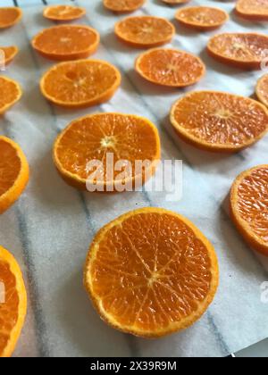 Mandarinen schneiden in Scheiben. Auf Lebensmittelpapier gelegt. Zum Trocknen und Dekorieren von Desserts. Stockfoto