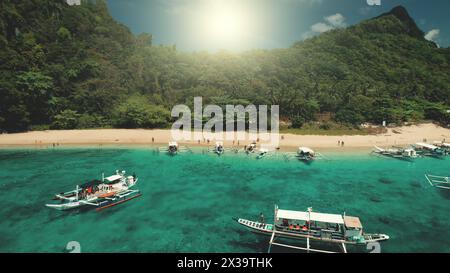 Segelboot mit Touristenjacht bei Sonnenuntergang am Meer Küste aus der Nähe aus der Vogelperspektive. Leute am Sandstrand. Tropische Natursonnenlandschaft. Grüne Klippenküste am sonnigen Sommertag. Berginsel El Nido, Philippinen, Asien Stockfoto