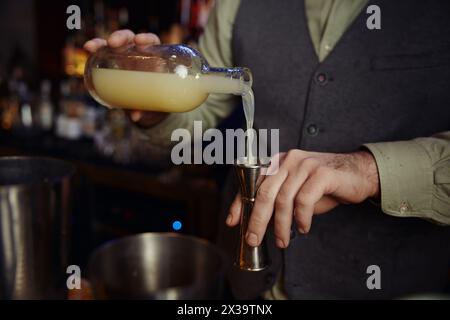 Nahaufnahme eines selbstbewussten Barkeepers, der Alkohol zum Cocktail schmeckt Stockfoto