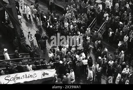 1960er Jahre, historische Familienmitglieder warten am Fuße einer Gangway eines Passagierschiffs am Dock in Southampton, England, Großbritannien. Der Name auf dem Banner ist Safmarine, kurz für South African Marine Corporation, eine südafrikanische Reederei. Das 1946 gegründete Unternehmen bot Fracht-, Fracht- und Containerschiffe an und betreibt von 1965 bis 1977 einen Passagierliniendienst zwischen Großbritannien und Südafrika mit zwei ehemaligen Schiffen der Union-Castle-Linie, der RMS Transvaal Castle und Pretoria Castle. Stockfoto