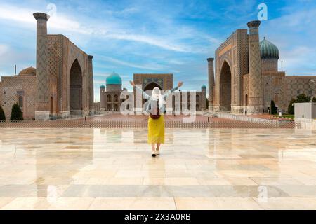 Usbekistan, Samarcanda - ein junges Mädchen, das mit offenen Armen auf den Registan-Platz steht Stockfoto