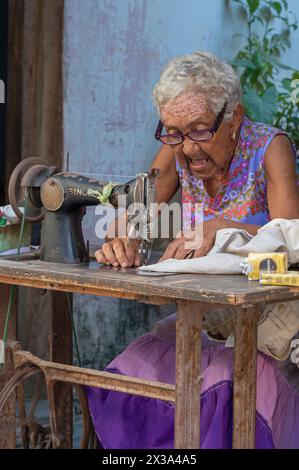 Eine alte Dame arbeitet mit ihrer Nähmaschine an einer Straßenecke in der Altstadt, Havanna, Kuba. Stockfoto