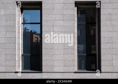 Zwei rechteckige Fenster mit grauen Doppelglasfenstern, in modernem Stil mit der Reflexion des Himmels und der Häuser auf dem Glas, gegen die Ba Stockfoto