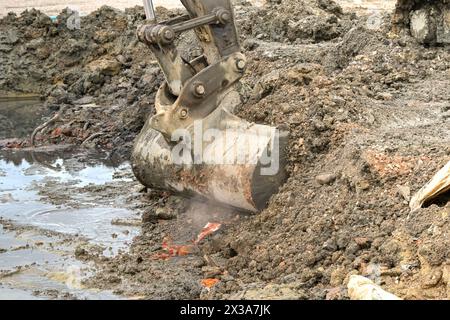 Schaufel eines Baggers, der Erde und Schutt auf einer Baustelle aufnimmt. Keine Personen. Stockfoto