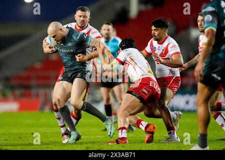 Huddersfield Giants’ Adam Swift (links) wird im Totally Wicked Stadium in St Helens im Spiel der Betfred Super League von Joe Batchelor (zweiter links) angegriffen. Bilddatum: Donnerstag, 25. April 2024. Stockfoto