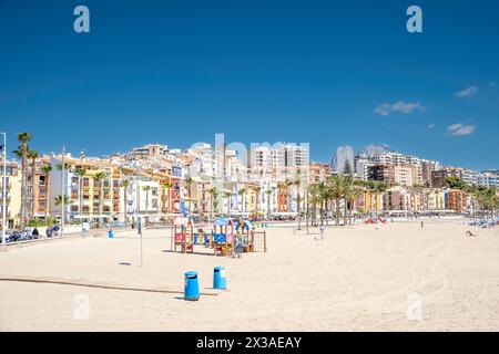 La Vila Joiosa, Spanien - 24. April 2024: Blick auf die wunderschöne Küstenstadt Villajoyosa. Strandpromenade mit farbenfrohen Häusern, Leute, die sich im Freien entspannen Stockfoto