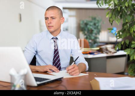 Professioneller Geschäftsmann mit Laptop am Arbeitsplatz im modernen Büro Stockfoto