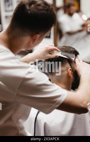 Der Friseur verwendet Haarschneider an der Stirn, am Ohr, am Kinn, am Tempel Stockfoto