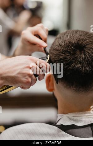 Der Friseur verwendet Haarschneider an der Stirn, am Ohr, am Kinn, am Tempel Stockfoto