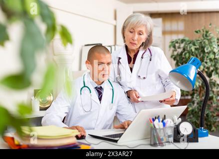 Ältere Ärztin im Büro mit männlichen Kollegen Stockfoto