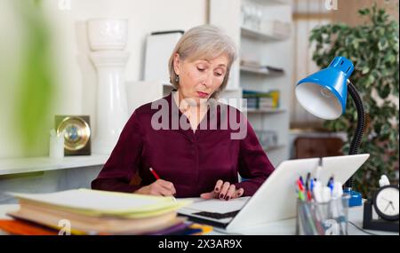 Verärgerte Frau mit Dokumenten in der Firma am modernen Arbeitsplatz Stockfoto