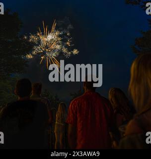 Buntes Feuerwerk am 4. Juli im Mittleren Westen mit dunklen Figuren, die Menschen beobachten Stockfoto