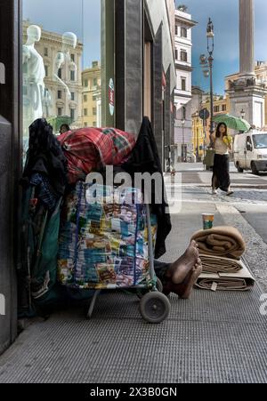 Italien, Rom: Ein Obdachloser sitzt auf dem Bürgersteig, geschützt von einem Trolley, der Euro-Banknoten von unterschiedlichem Wert darstellt Stockfoto