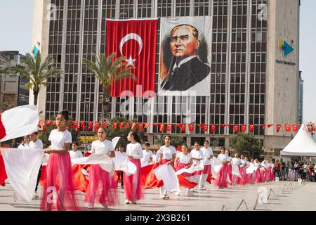 Izmir, Türkei - 23. April 2024: Fröhlicher Tanz von Kindern in Rot und weiß, mit türkischen Fahnen und Atatürks Porträt im Hintergrund während Nat Stockfoto