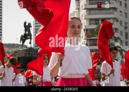 Izmir, Türkei - 23. April 2024: Eine Nahaufnahme eines jungen Schülers mit einer türkischen Flagge, während Mitteilnehmer im Hintergrund Fahnen schwenken, du Stockfoto