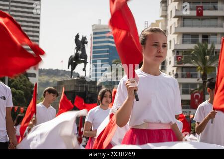 Izmir, Türkei - 23. April 2024: Eine Nahaufnahme eines jungen Schülers mit einer türkischen Flagge, während Mitteilnehmer im Hintergrund Fahnen schwenken, du Stockfoto