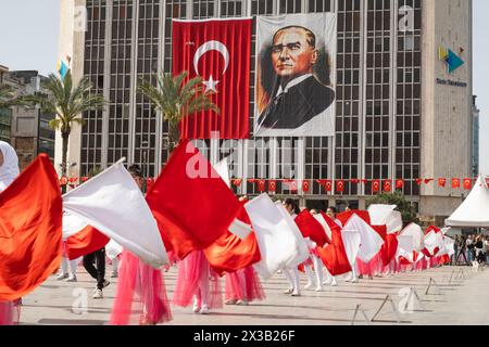 Izmir, Türkei - 23. April 2024: Fröhlicher Tanz von Kindern in Rot und weiß, mit türkischen Fahnen und Atatürks Porträt im Hintergrund während Nat Stockfoto