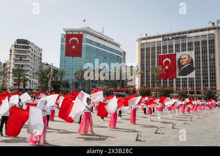 Izmir, Türkei - 23. April 2024: Fröhlicher Tanz von Kindern in Rot und weiß, mit türkischen Fahnen und Atatürks Porträt im Hintergrund während Nat Stockfoto