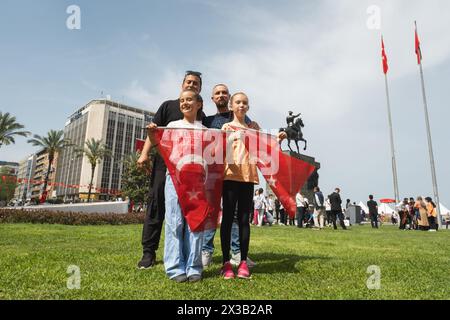 Izmir, Türkei - 23. April 2024: Während der Feierlichkeiten zum Kindertag auf dem Platz der Republik stehen zwei Mädchen mit Fahnen stolz mit ihrem Vater, mit dem Stockfoto