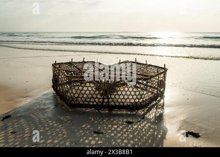 Alter Fischkäfig im Wasser der Karibik unter blauem tropischem Himmel. Käfigfischen und Ebbe auf den französischen Antillen. Afrikanische Fangfalle für Katzen Stockfoto