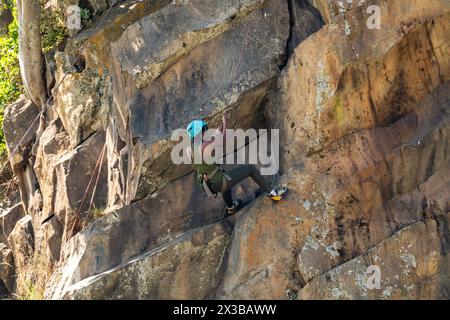 Hell's Gate National Park, Kenia. 7. Februar 2024: Junge afroamerikanerin klettert entlang der Granitklippe. Das Mädchen hält sich am Sicherheitsseil fest Stockfoto