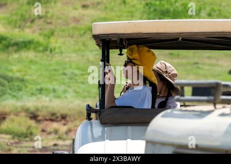 Amboseli-Nationalpark, Kenia. 5. Februar 2024: Ein junges Mädchen macht Fotos von einem Safari-Auto. Stockfoto