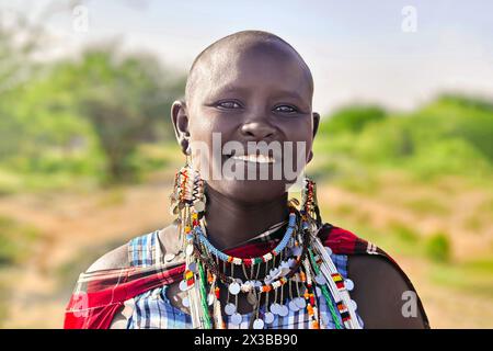 Februar 2024. Amboseli Nationalpark. Kenia: Eine junge Maasai-Frau in traditionellem rotem Kleid und Perlenschmuck steht vor dem Hintergrund Stockfoto