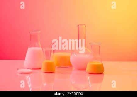 Eine florentiner Flasche mit flachem Boden, eine Petrischale, ein Becher und konische Kolben mit Flüssigkeit, die auf einem Hintergrund mit Farbverlauf angeordnet sind. Forschungsinhalte Stockfoto