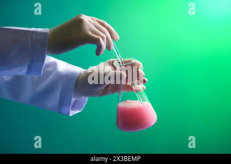 Wissenschaftler mit weißen Handschuhen rührt die Chemikalie mit einem Glasstab um. Medizingerätes Experiment und chemisch-biologisches Studium in wissenschaftlichen Laboren Stockfoto